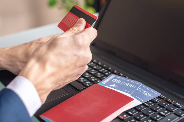 Hombre con tarjeta de débito en la mano compra en los billetes de avión de Internet utilizando un ordenador portátil. El concepto de compra y reserva en línea
 - Foto, imagen