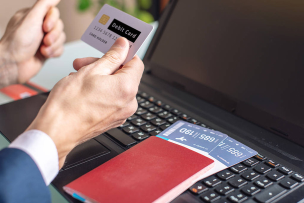 Hombre con tarjeta de débito en la mano compra en los billetes de avión de Internet utilizando un ordenador portátil. El concepto de compra y reserva en línea
 - Foto, Imagen