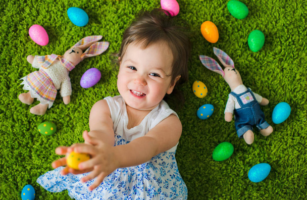 El niño se acuesta en la hierba con huevos de Pascua y una liebre
 - Foto, imagen