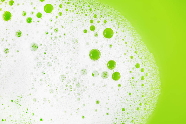 Espuma de jabón con burbujas sobre fondo verde. Jabón sud en agua. Concepto de detergente. Puesta plana
. - Foto, imagen