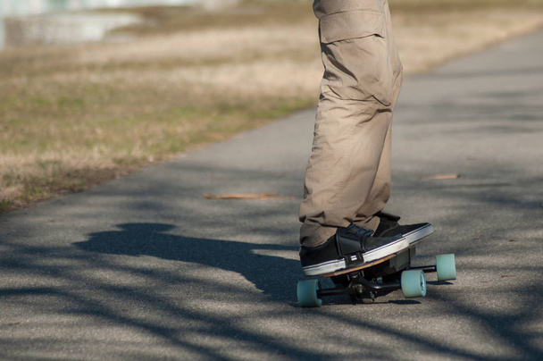 closeup of legs of man on electric skate board on the road - Foto, Imagem