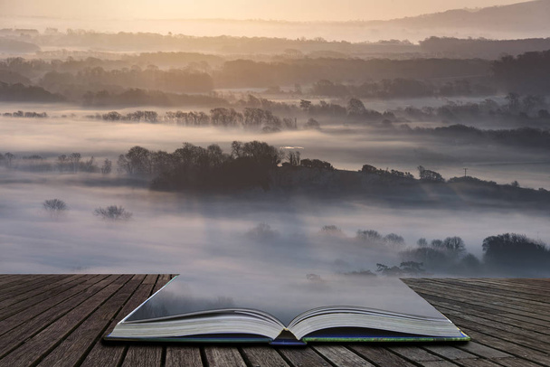 Beautiful foggy English countryside landscape at sunrise in Winter with layers rolling through the fields coming out of pages in magical story book - Photo, Image