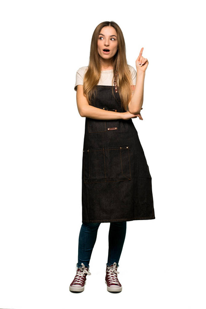 Full body Young woman with apron thinking an idea pointing the finger up on isolated background - Foto, Imagem