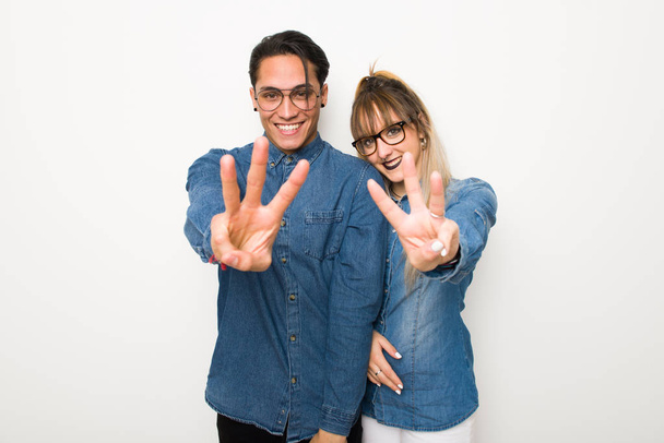 Νεαρό ζευγάρι με γυαλιά ευτυχισμένο και μετρώντας τρία με δάχτυλα - Φωτογραφία, εικόνα