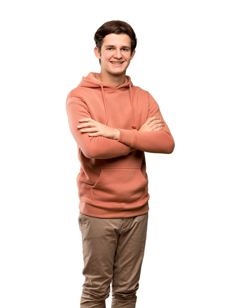 Teenager man with sweatshirt with arms crossed and looking forward over isolated white background - Foto, afbeelding