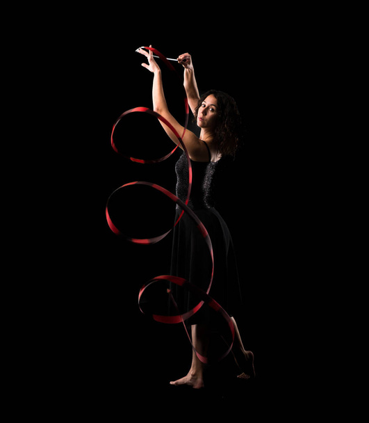 Γυναίκα κάνει ρυθμική γυμναστική με κορδέλα σε μαύρο φόντο - Φωτογραφία, εικόνα