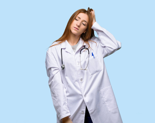 Руда жінка-лікар з вираженням розчарування і не розумінням на ізольованому синьому фоні
 - Фото, зображення