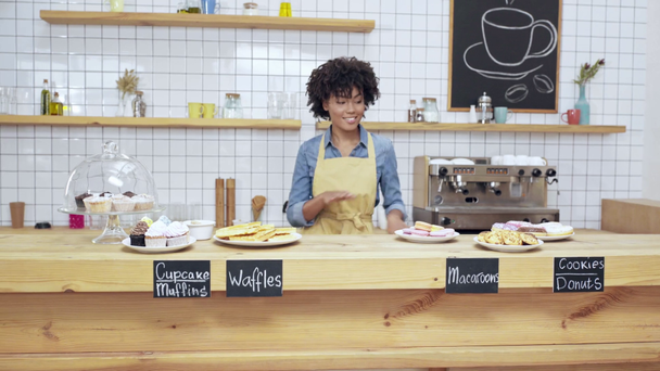 güzel gülümseyen Afrikalı-Amerikalı kadın Kafe sahibi tatlılar tezgahın arkasındaki dans önlük - Video, Çekim