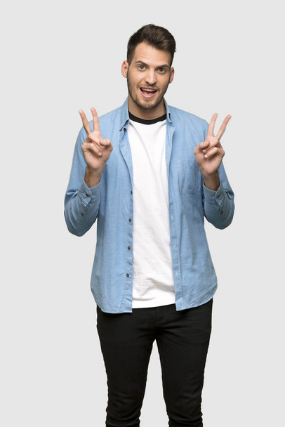 Handsome man smiling and showing victory sign with both hands over grey background - Photo, image