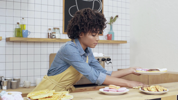 güzel Afrikalı-Amerikalı kadın Kafe sahibi önlük tatlılar sayaç üzerinde ayarlama - Video, Çekim