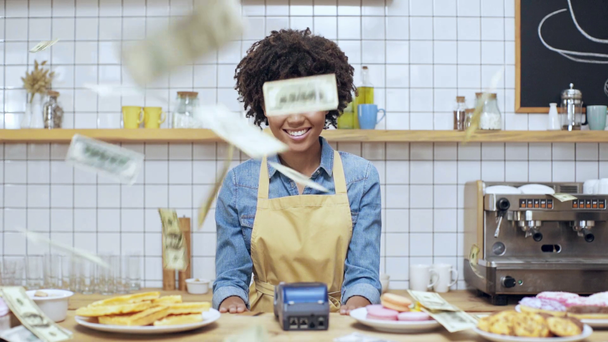 prachtige Afrikaanse Amerikaanse vrouwelijke kassier via creditcard en terminal in café, camera kijken en lachend met geld vallen op achtergrond - Video