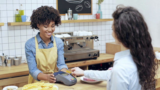 belle caissière afro-américaine tenant terminal tandis que la femme payant avec carte de crédit dans le café
 - Séquence, vidéo