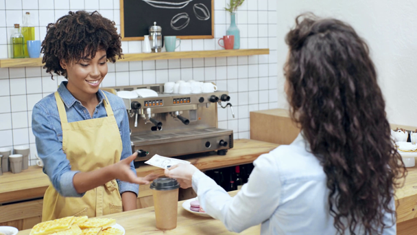 Kundin bezahlt mit Bargeld afrikanisch-amerikanische Kassiererin und holt Kaffee für Café - Filmmaterial, Video