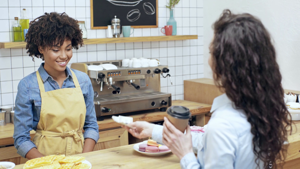 θηλυκό πελάτη πληρωμή με μετρητά αφρικανικές αμερικανικές γυναίκες ταμία και μαζεύοντας καφέ για να πάει στο καφενείο - Πλάνα, βίντεο