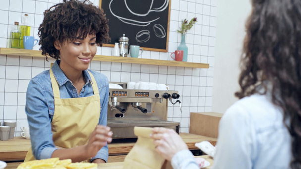 vrouwelijke klant betalen met contant geld, mooie Afrikaanse Amerikaanse vrouwelijke kassier en afhalen bestelling in café - Video