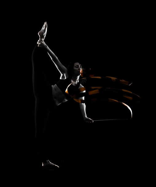 Siyah arka plan üzerine şerit ile ritmik jimnastik yapıyor kadın - Fotoğraf, Görsel