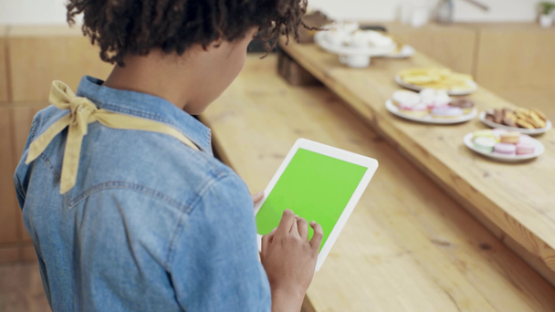 Achteraanzicht van Afro-Amerikaanse vrouwelijke kassier digitale tablet met groen scherm in café - Video