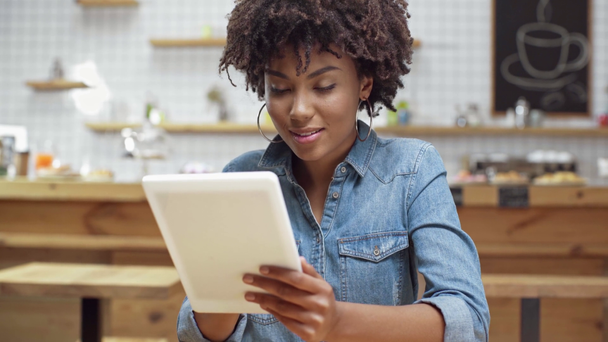messa a fuoco selettiva bella cliente afroamericana donna utilizzando tablet digitale e sorridente in caffè
 - Filmati, video