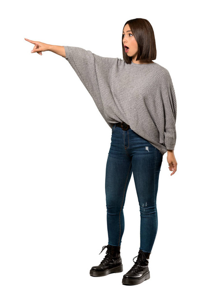 A full-length shot of a Young woman pointing away over isolated white background - Photo, Image