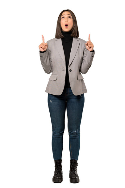 Een full-length shot van een jonge zakenvrouw wijzen omhoog en verbaasd over geïsoleerde witte achtergrond - Foto, afbeelding
