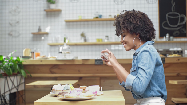 güzel gülümseyen Afrikalı-Amerikalı kadın müşteri alarak fotoğraf pasta Cafe Smartphone  - Video, Çekim