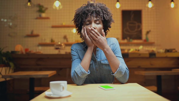mooie triest Afro-Amerikaanse vrouwelijke klant stutten kin met de hand tijdens het wachten voor iemand in café - Video