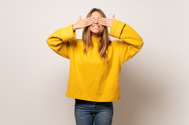 Mujer con suéter amarillo sobre pared aislada cubriendo los ojos con las manos. Sorprendido de ver lo que está por venir
 - Foto, Imagen