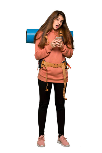 Full-length shot of Hiker girl sending a message with the mobile on isolated white background - Foto, Imagen