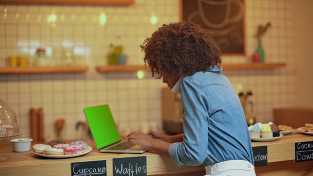 krásné usmívající se žena na volné noze pomocí přenosného počítače s prázdnou obrazovkou a mluví na smartphone v kavárně - Záběry, video
