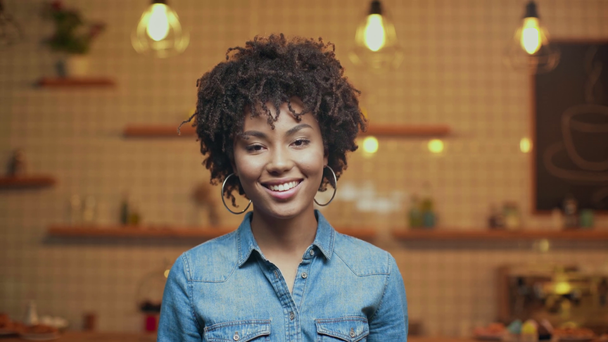 kamera Cafe bakarak denim bluz içinde güzel gülümseyen Afrikalı-Amerikalı kadın seçici odak - Video, Çekim