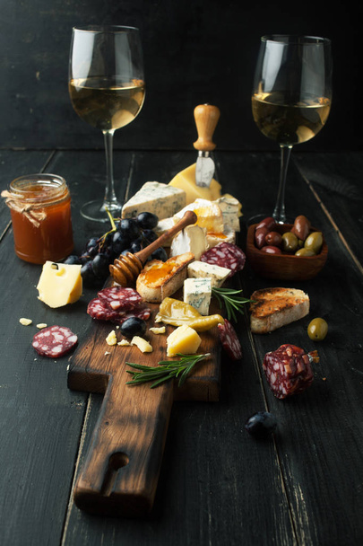 Assorted cheeses with grapes, nuts and rosemary on a wooden backgroun - Foto, imagen