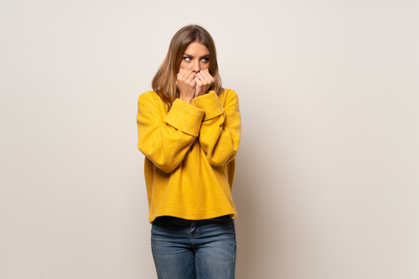 Frau mit gelbem Pullover über isolierter Wand nervös und verängstigt - Foto, Bild