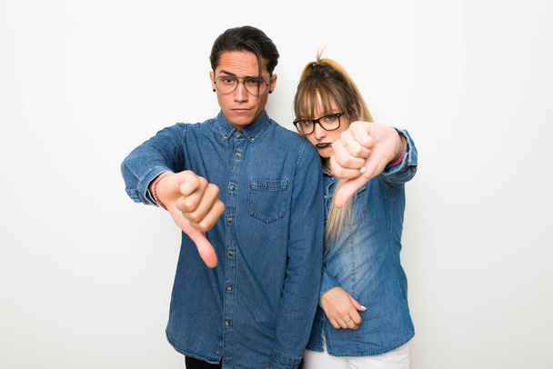 Jeune couple avec des lunettes montrant pouce vers le bas signe avec expression négative
 - Photo, image