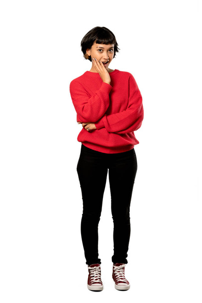 A full-length shot of a Short hair girl with red sweater surprised and shocked while looking right over isolated white background - Photo, Image