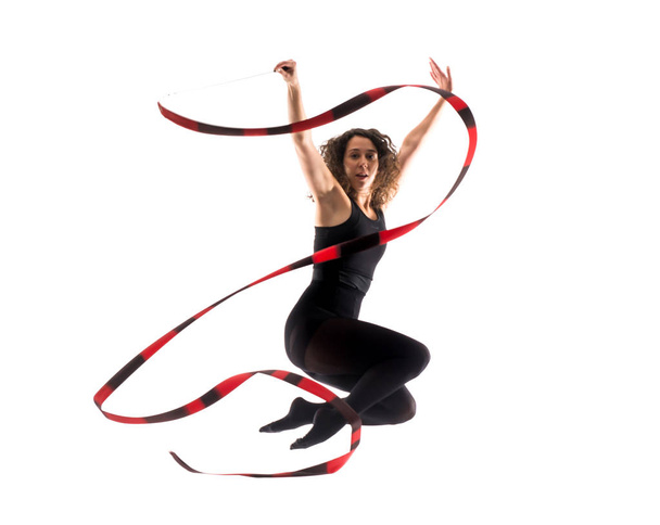 Vrouw doet ritmische gymnastiek met lint op geïsoleerde witte achtergrond - Foto, afbeelding