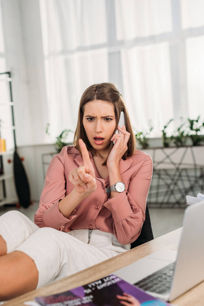 Selektivní fokus šokovaná žena mluvila na smartphone při pohledu na nehty doma - Fotografie, Obrázek