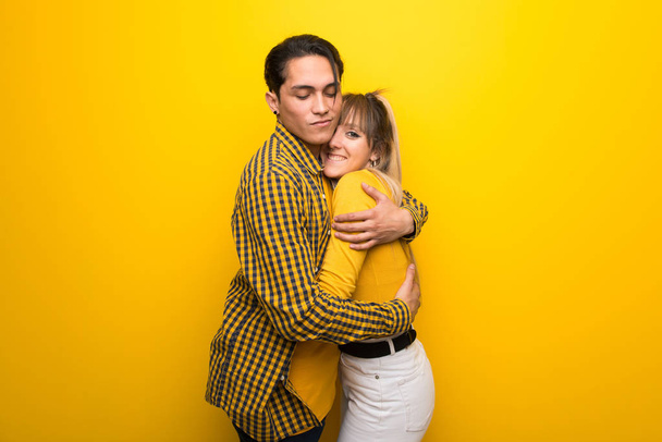 Young couple hugging on vibrant yellow background - Photo, Image