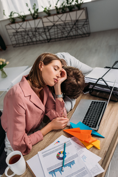 girlfriend and boyfriend sleeping at desk near laptop and cup with drink - Foto, afbeelding