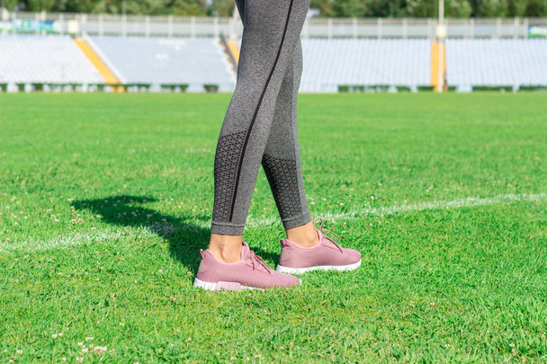 白い線とサッカーのフィールドに立っているピンクのスニーカーの女性。スタジアムで実行の準備ができて. - 写真・画像