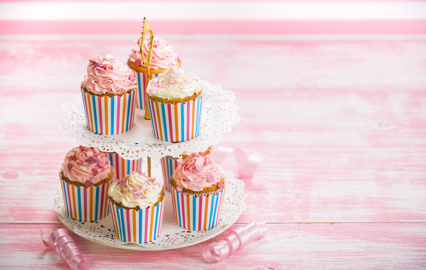close up view of sweet cupcakes with cream on pink and white background - Фото, зображення