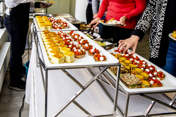 bruschetta on grilled bread with vegetable ratatouille, quiche loren and a mini burger with fried mackerel, tartar sauce, fresh cucumber and ice salad. at catering event on some festive event, party or wedding reception  - Photo, Image