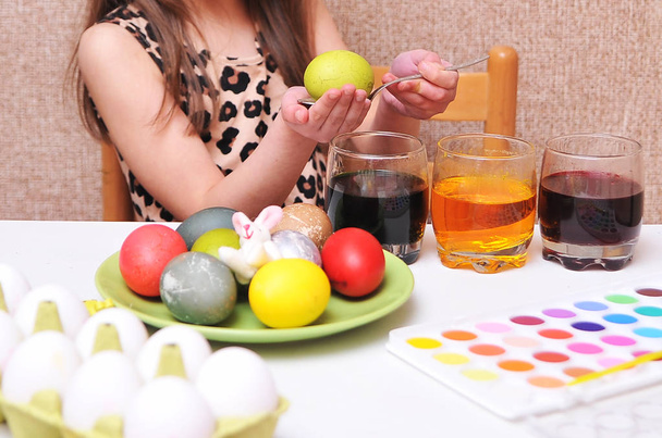 Linda niña pintando huevos de Pascua en casa
. - Foto, imagen