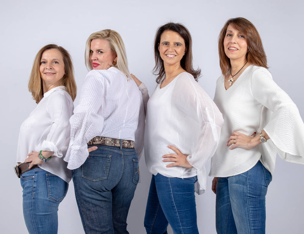 Groupe de 4 femmes, amies, d'âge moyen s'amusant dans une séance photo dans un studio avec fond blanc
 - Photo, image
