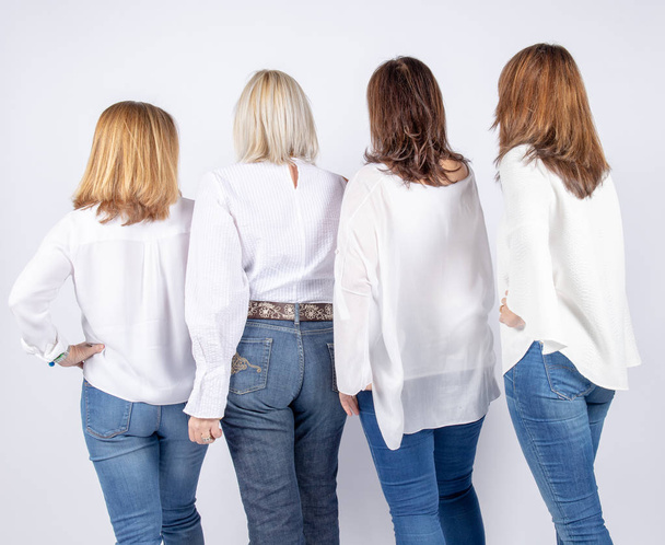 Group of 4 women, friends, middle-aged having fun in a photo session in a studio with white background - Photo, Image