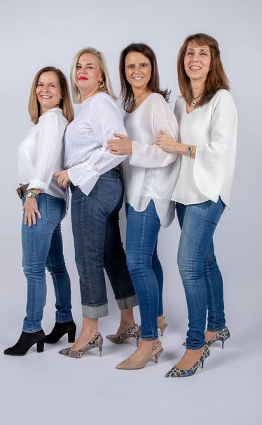 Groupe de 4 femmes, amies, d'âge moyen s'amusant dans une séance photo dans un studio avec fond blanc
 - Photo, image