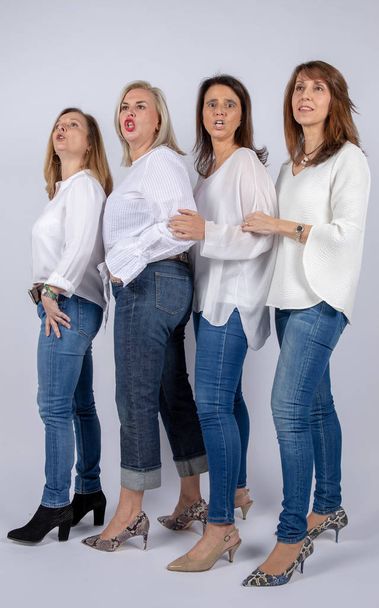 Grupo de 4 mujeres, amigas, de mediana edad divirtiéndose en una sesión de fotos en un estudio con fondo blanco
 - Foto, Imagen