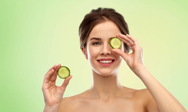 smiling woman with cucumber over green background - Foto, immagini