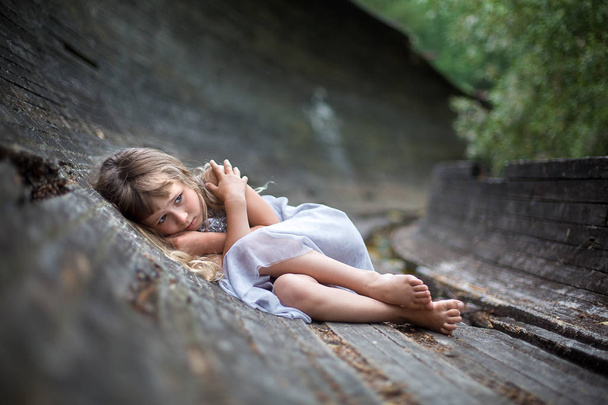 Портрет наляканої дівчинки. Налякана, заморожена маленька дівчинка лежить сама в лісі
. - Фото, зображення