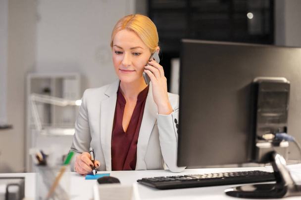 businesswoman calling on sartphone at night office - Foto, Imagem