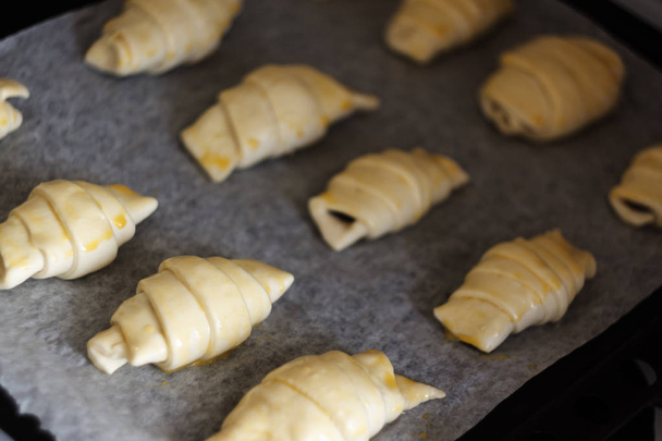 Raw croissants with chocolate on a baking sheet before baking. - Foto, imagen